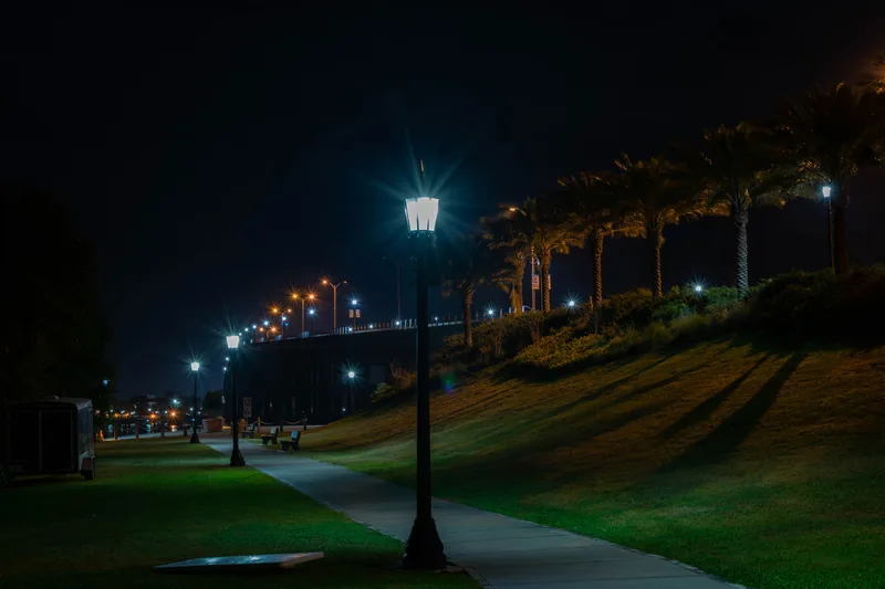 A lamp lit walkway by the Halifax River at night, near the Granada Bridge in Ormond Beach