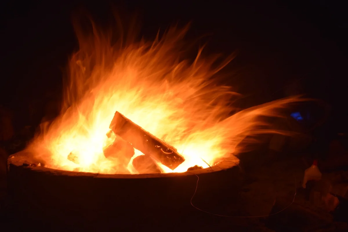 A bonfire blazing in a fire pit at night