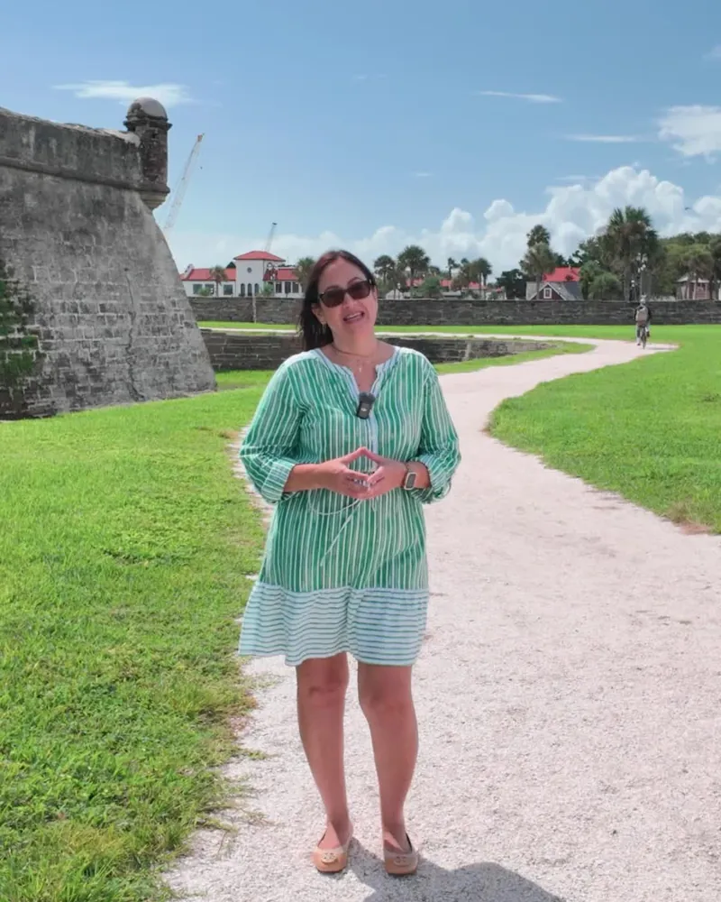 Marilynn Wolfe speaking to camera on a path beside an old stone fort