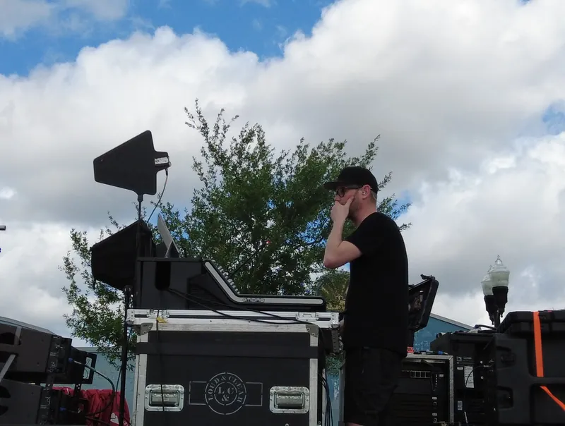 A crew member working at a speaker stack on stage