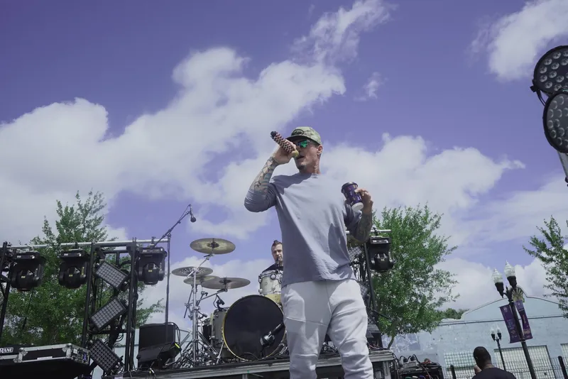 The artist on stage with the microphone raised against a big sky