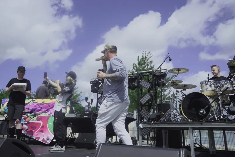 The artist with band members on stage in front of a graffiti backdrop