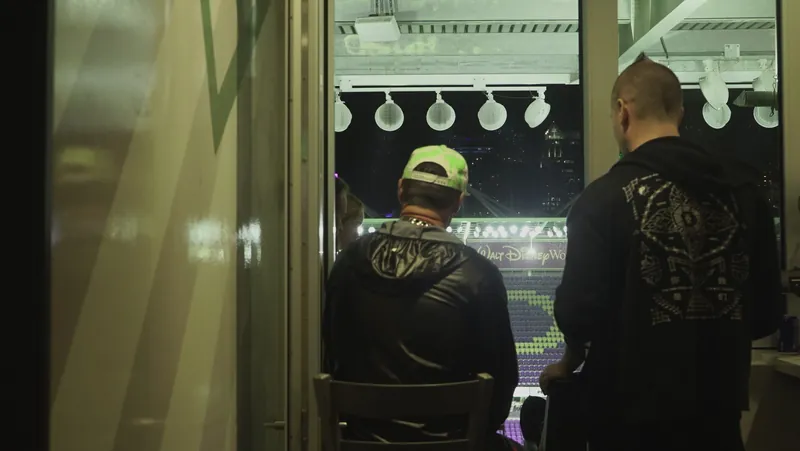 Two people looking out of a window toward the stadium lights