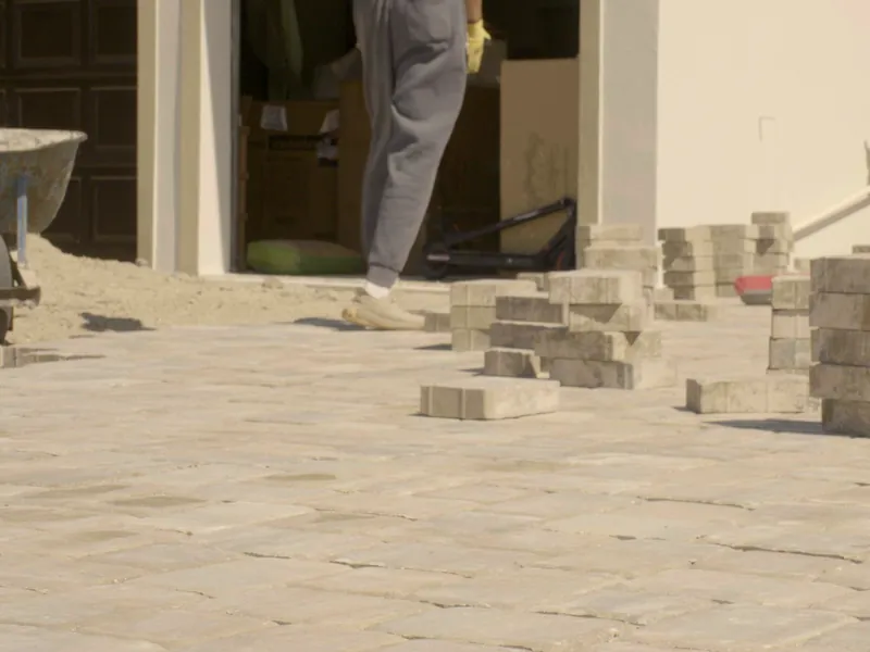 Stacks of pavers on a freshly laid driveway in front of an open garage