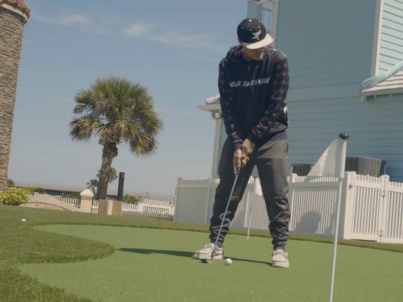 Vanilla Ice lining up a putt on a backyard green